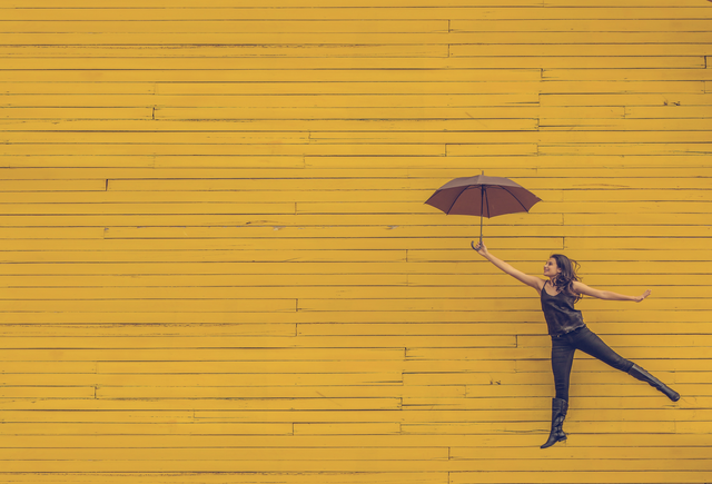 Jumping woman with umbrella for IRS update on employee benefits in 2018