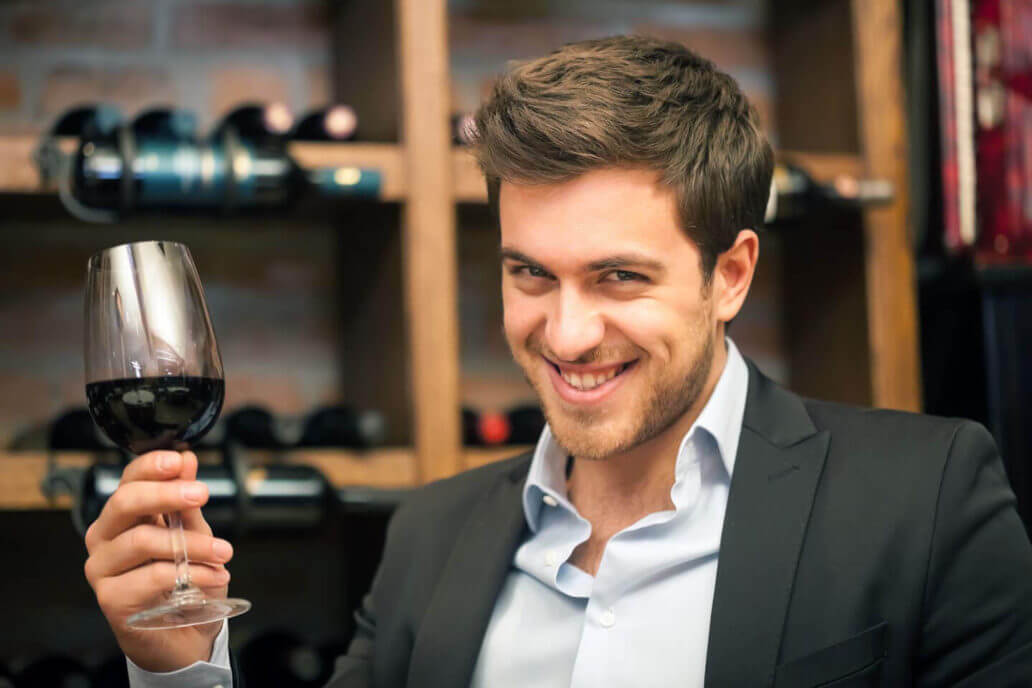 Man smiling with a glass of wine working on business relationships